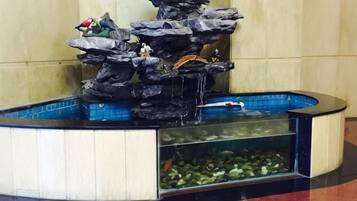 A rock waterfall fountain with fish tanks below.