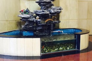 A rock waterfall fountain with fish tanks below. - Jinlong Hotel (Dongguan)