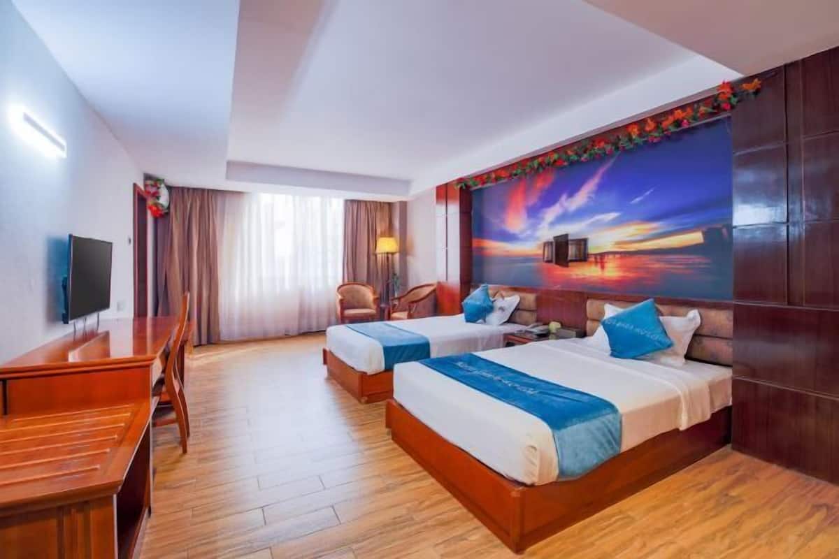 A hotel room with two beds, a desk, a TV, and a large painting on the wall.