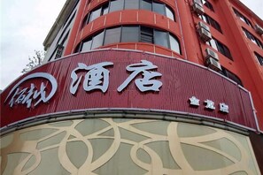Un edificio con una fachada roja destacada y un cartel que indica un hotel.