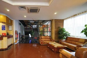 A hotel lobby with a reception desk, seating area, and a staircase leading to the upper floors. - Jinlong Hotel (Dongguan)