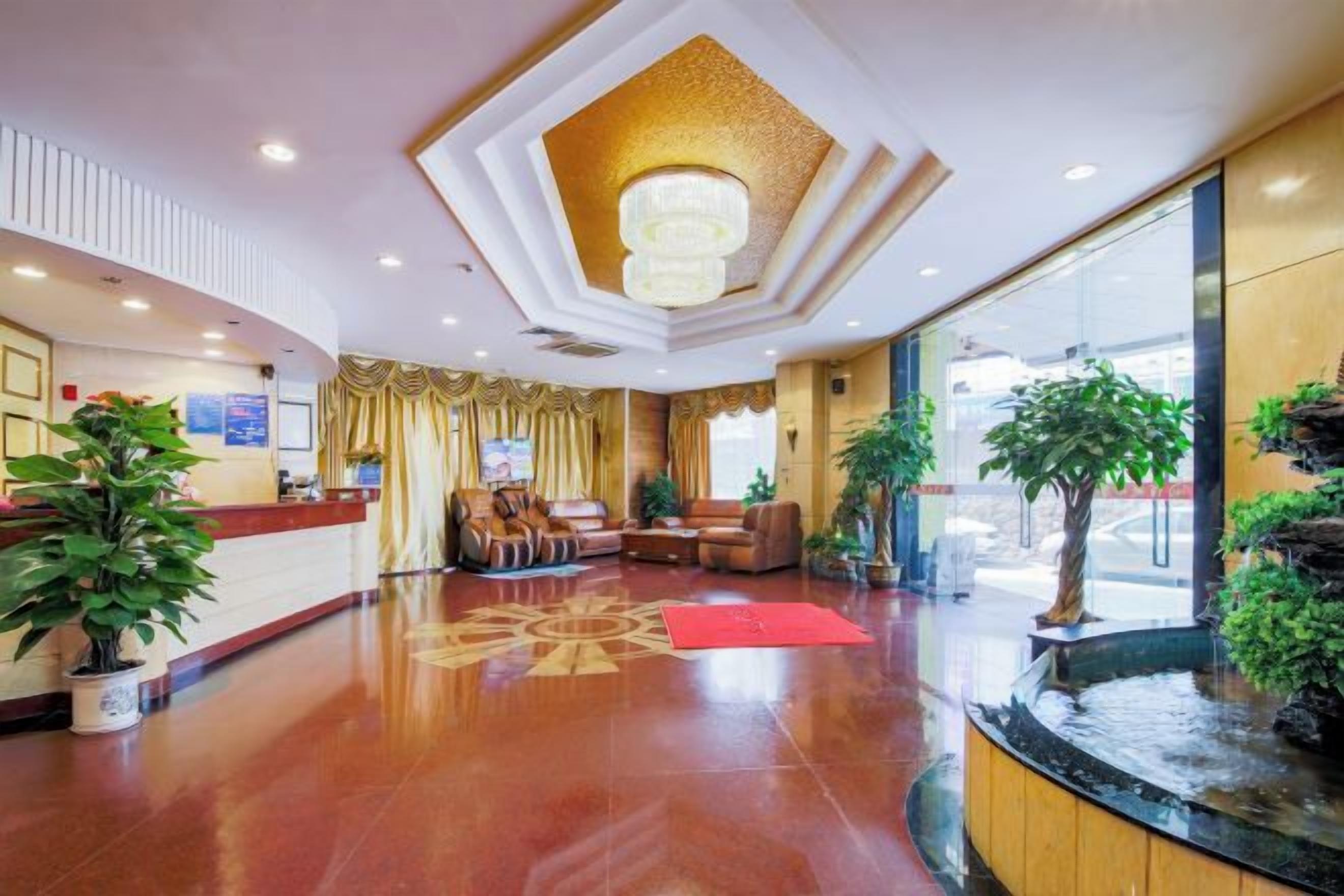 A hotel lobby with a reception desk, seating area, and a water feature.
