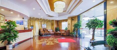 A hotel lobby with a reception desk, seating area, and a water feature.
