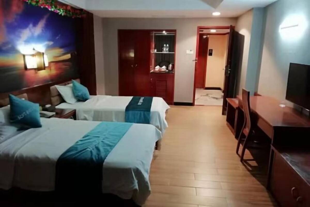 A hotel room with two beds, a TV, a desk, and a wardrobe.