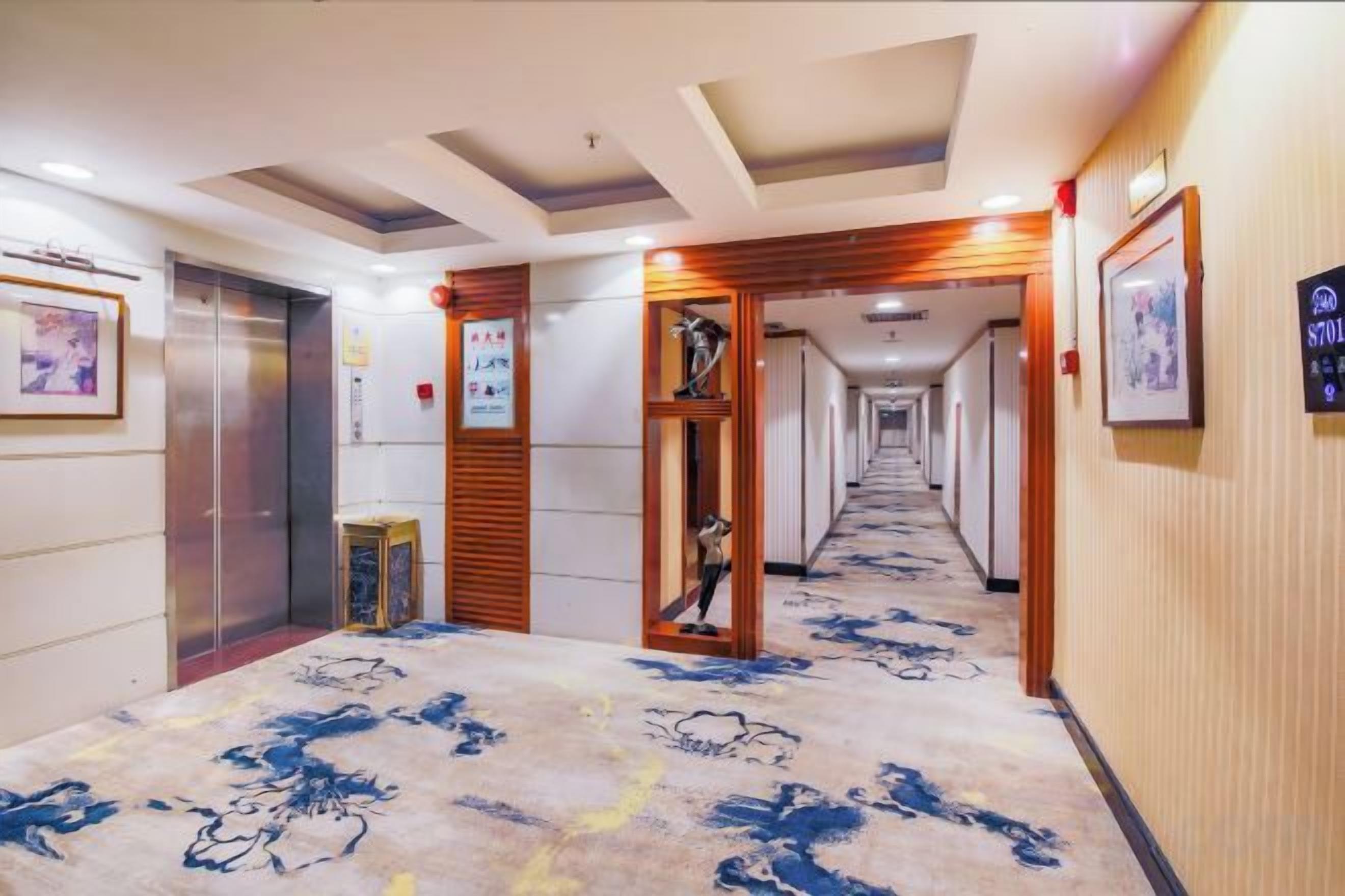 A hotel corridor with a carpeted floor, wooden paneling, and framed pictures on the walls.