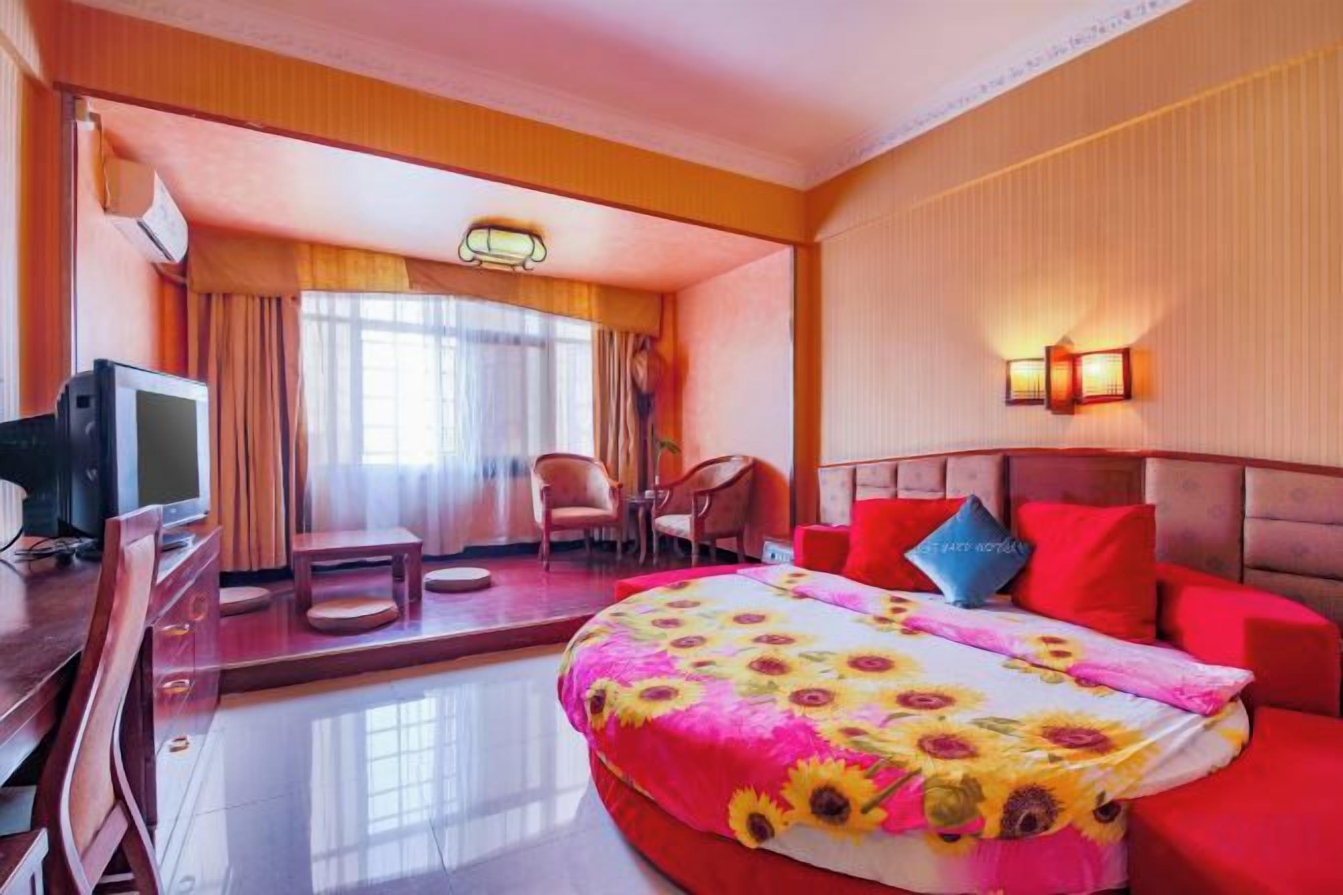 Una camera d'albergo con un letto, una scrivania con televisore, una poltrona e un divano.