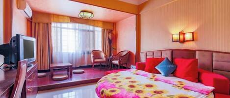 Una camera d'albergo con un letto, una scrivania con televisore, una poltrona e un divano.