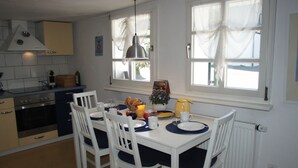 A kitchen with white cabinets, a stove, and a dining table set for breakfast. - The small Villa OLEFant in the historic center of Schleiden Olef (Schleiden)