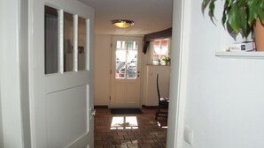 A hallway with a white door, a window with curtains, and a potted plant on a shelf. - The small Villa OLEFant in the historic center of Schleiden Olef (Schleiden)