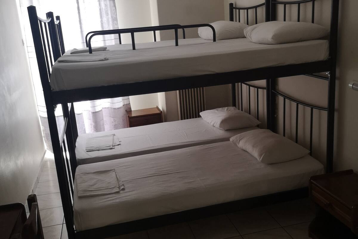 A bunk bed room with a window, a radiator, and a small wooden table.