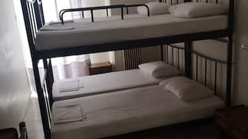 A bunk bed room with a window, a radiator, and a small wooden table.