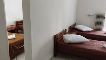 Een kamer met twee houten bedden, witte wanden en een radiator.
