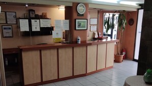 A reception area with a wooden counter, framed certificates, a clock, and a reception sign.