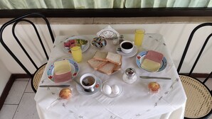 A breakfast table set with plates of toast, eggs, and beverages, surrounded by chairs.