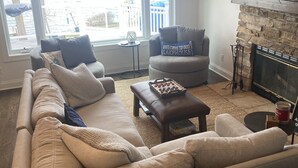 A living room with a beige sofa, a gray armchair, a coffee table, and a fireplace. - Beautiful lakefront view on Lauderdale Lakes only steps away from golf course.  (Elkhorn)
