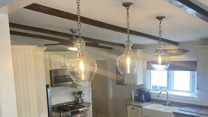 A modern kitchen with a central island, pendant lights, and bar stools. - Beautiful lakefront view on Lauderdale Lakes only steps away from golf course.  (Elkhorn)