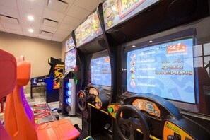 A racing game arcade with multiple screens displaying racing games and a steering wheel controller. - Last Minute Disney! Private Pool, Hot Tub, Game Room & Themed Bedrooms. Book Now! #39408 (Orlando)