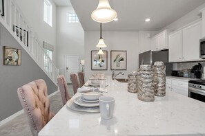Een moderne keuken met witte kasten, een marmeren eiland en roestvrijstalen apparatuur.