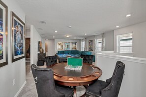 Een ruime kamer met een pooltafel, een biljarttafel en een ronde tafel met stoelen.