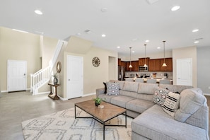 A modern living room with a sectional sofa, a coffee table, and a staircase leading to another level.
