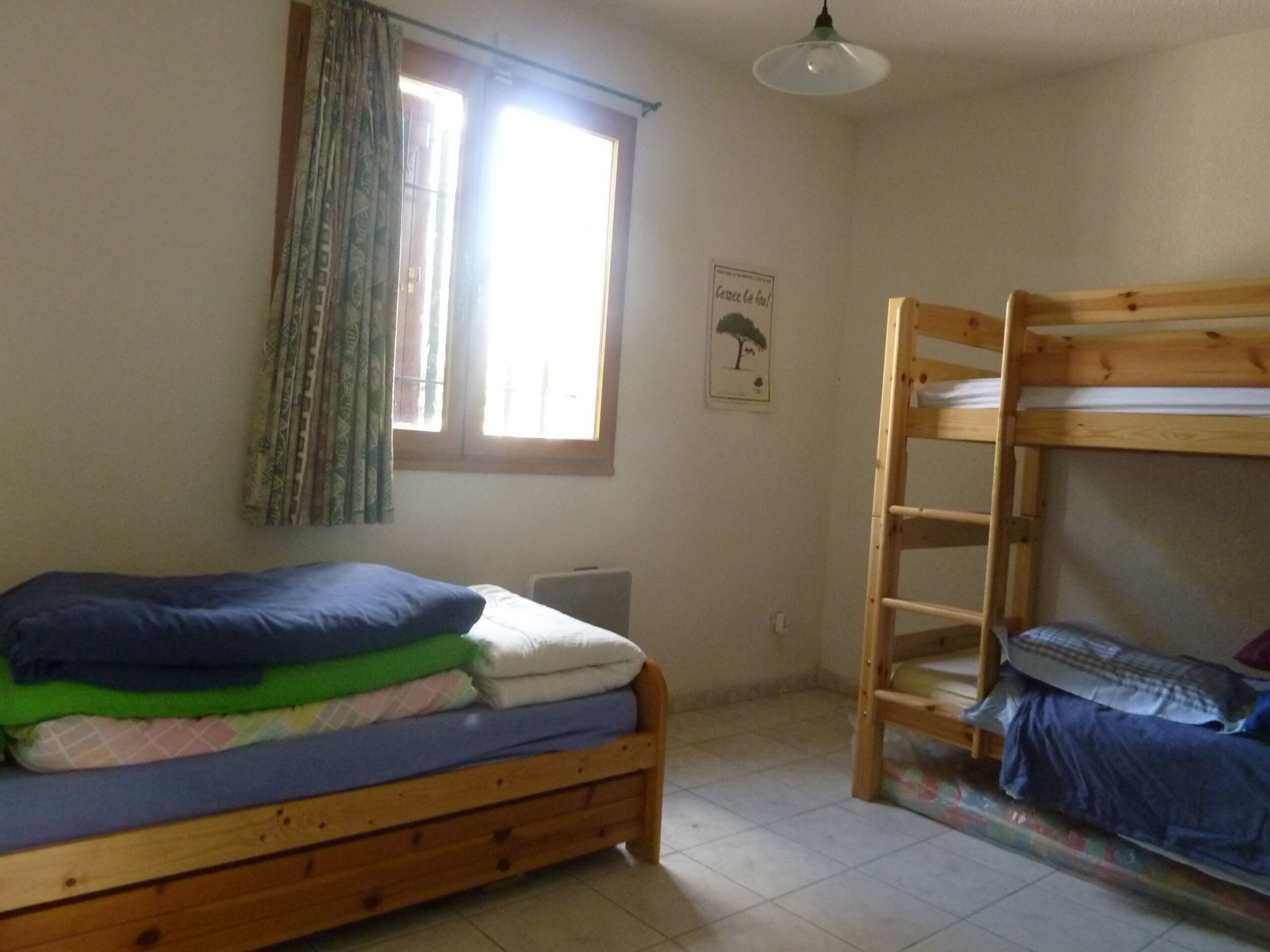 Ein Schlafzimmer mit Etagenbett, einem fenster mit Vorhängen, einer Heizung und einem Poster an der Wand.