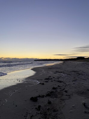 A beach with waves, a clear sky, and distant land. - Bella Casa Baabe (Ostseebad Baabe)