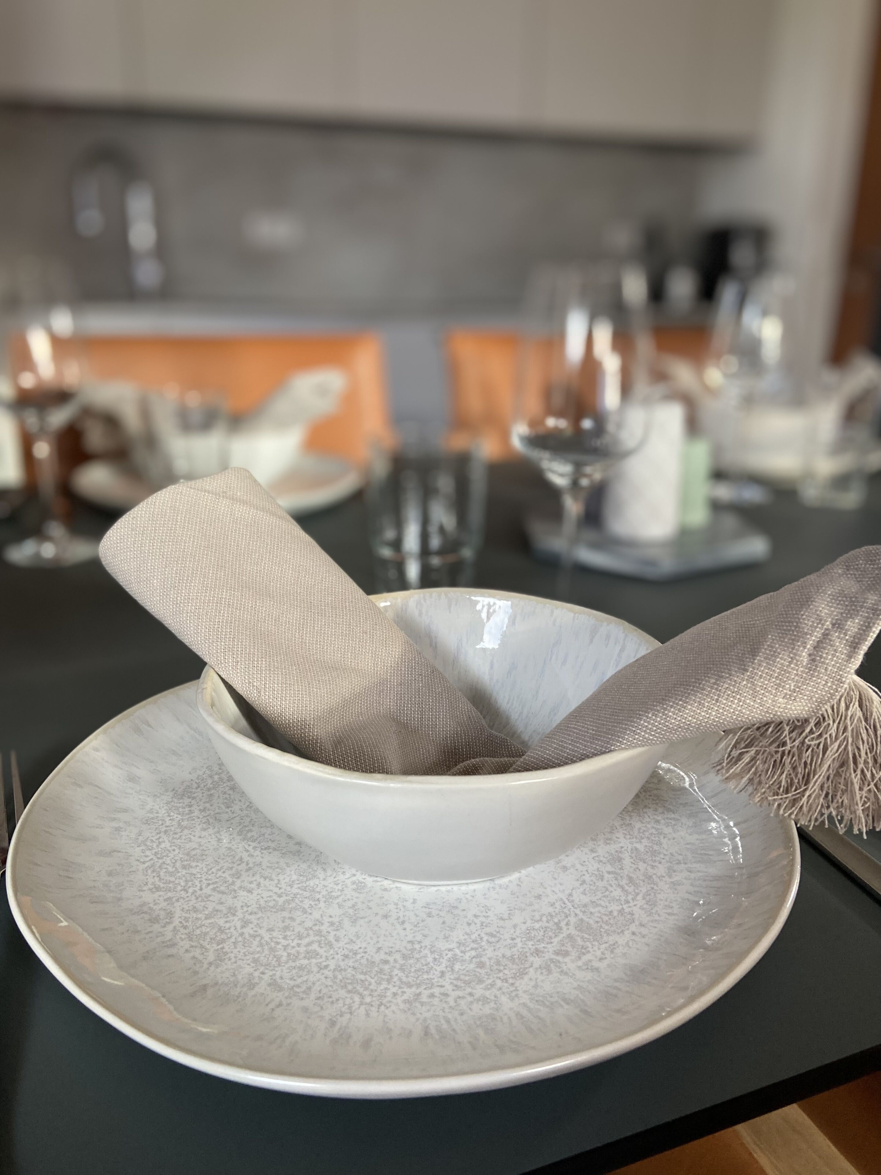 A dining table with a bowl and a cloth on a plate.