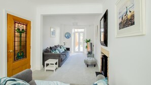Ein Wohnzimmer mit einer Couch, einem Couchtisch, einem Kamin und einer Tür mit einem Buntglasdekor.