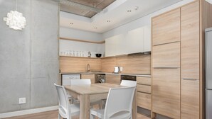 Cocina moderna con una mesa y sillas de madera, electrodomésticos integrados y una lámpara colgante.