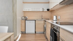 Cocina compacta con lavavajillas, lavadora y cafetera sobre la encimera.