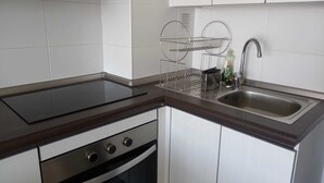 A kitchen with a stove, oven, sink, and a dish rack.