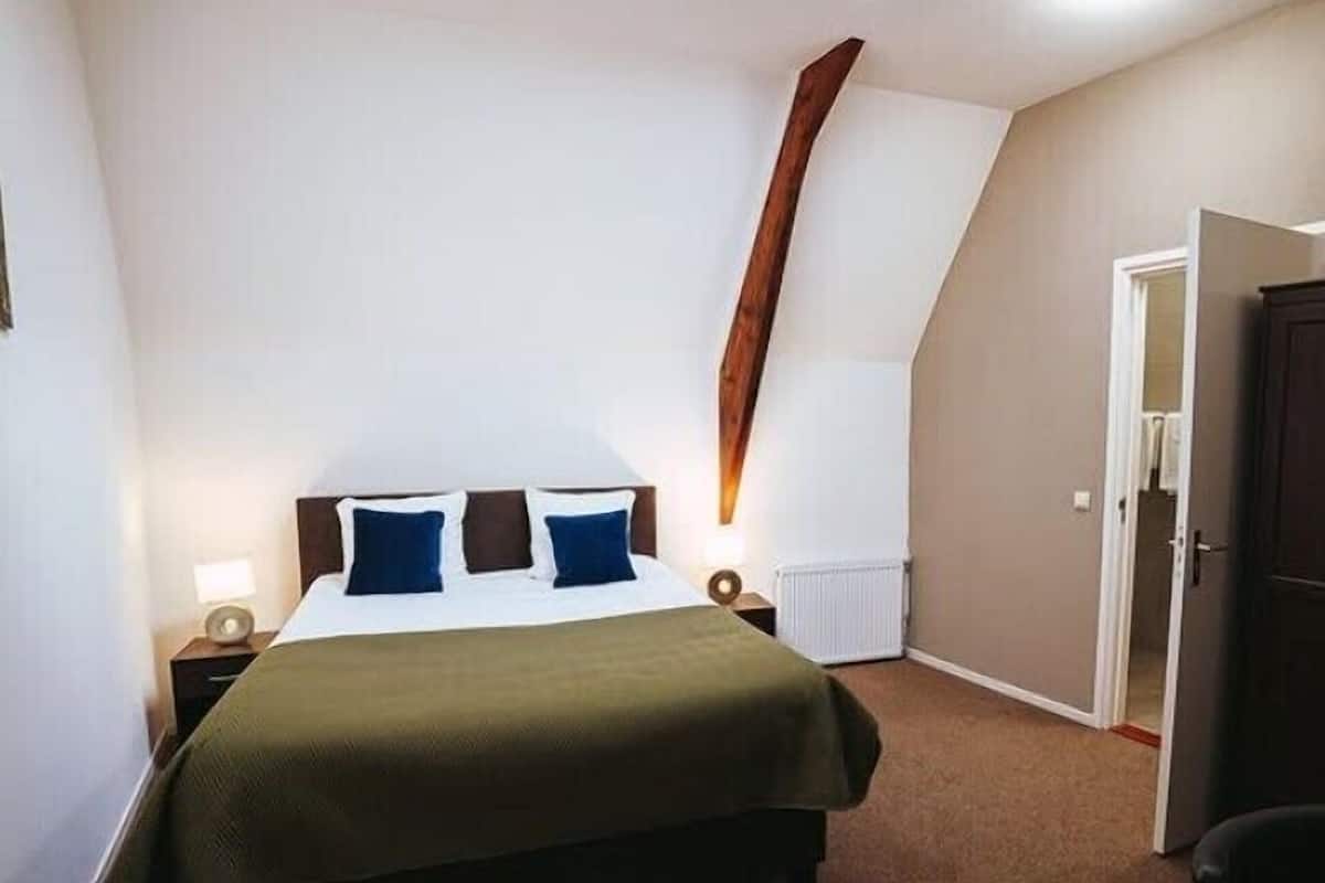 A bedroom with a bed, bedside tables, a radiator, and a wardrobe.