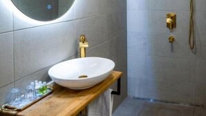 Un baño moderno con un espejo redondo, un lavamanos blanco y una zona de ducha.