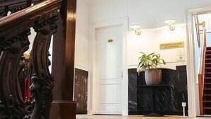 Una imponente escalera con peldaños alfombrados de rojo que conducen a una puerta blanca.