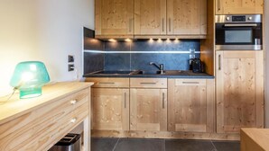 Une cuisine moderne avec des meubles en bois, un évier en acier inoxydable et un four encastré.