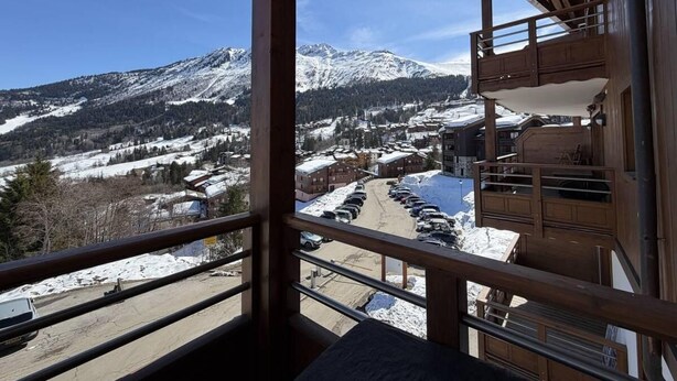 Un balcon avec vue sur une montagne enneigée et un espace de stationnement.