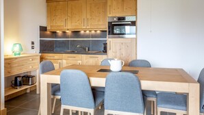 Une cuisine moderne avec des meubles en bois, un four en acier inoxydable et une table à manger avec des chaises.