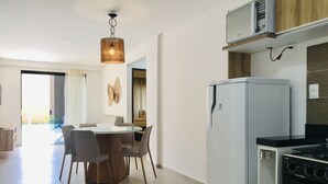 Una cocina moderna equipada con refrigerador, microondas y estufa. Hay una zona de comedor con una mesa y sillas.