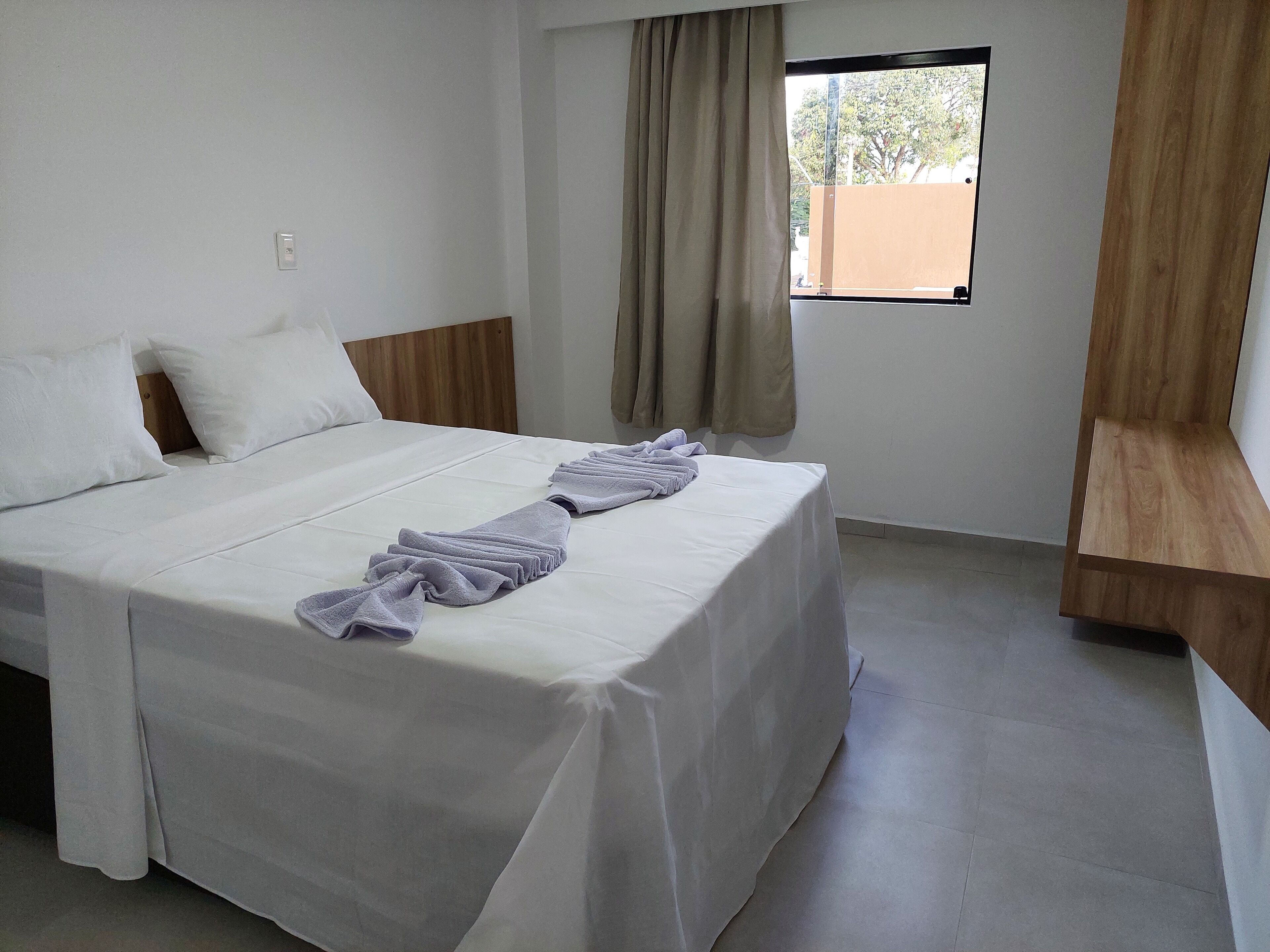 A neatly made bed with a white bedspread and a folded towel.