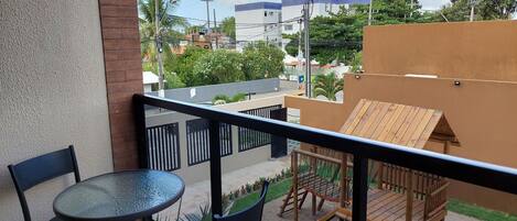 Un balcon avec une table et des chaises, une structure de jeu en bois et une vue sur le quartier environnant.