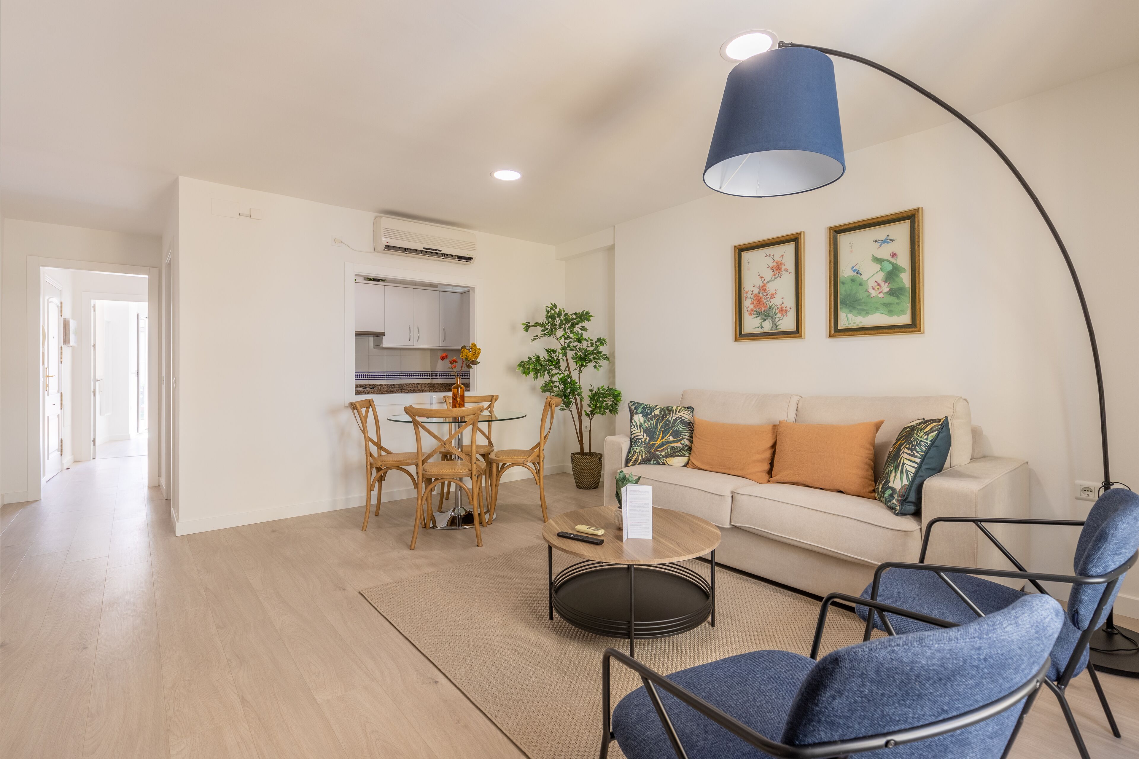 A modern living room with a sofa, two chairs, a coffee table, and a dining area with a table and chairs.