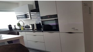 A modern kitchen with white cabinets, a built-in oven, and a microwave. - Lounge 2 - Top apartment approx. 72sqm, air conditioning, parking at the house, all in (Koblenz)