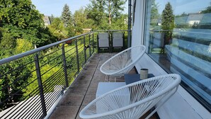 A balcony with two white wicker chairs and a small table, overlooking a garden and trees. - Lounge 2 - Top apartment approx. 72sqm, air conditioning, parking at the house, all in (Koblenz)