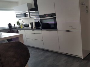 Una cocina moderna con armarios blancos, horno empotrado y microondas.