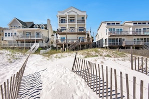 Une propriété située en bord de mer, comprenant des maisons à plusieurs étages, des passerelles en bois et une plage de sable.