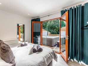 A bedroom with a bed, a hot tub, and a sliding glass door leading to an outdoor area. - Waterside Lodge Six - UK38264 (Elland)