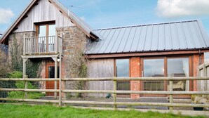 A rustic building with a stone facade, a wooden balcony, and a metal roof.