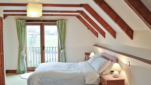 A bedroom with a bed, bedside tables, a wooden dresser, and a window with curtains.
