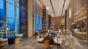 A spacious lobby with a long reception desk, comfortable seating areas, and large windows offering views of the cityscape. - HUALUXE Yibin by IHG (Yibin)