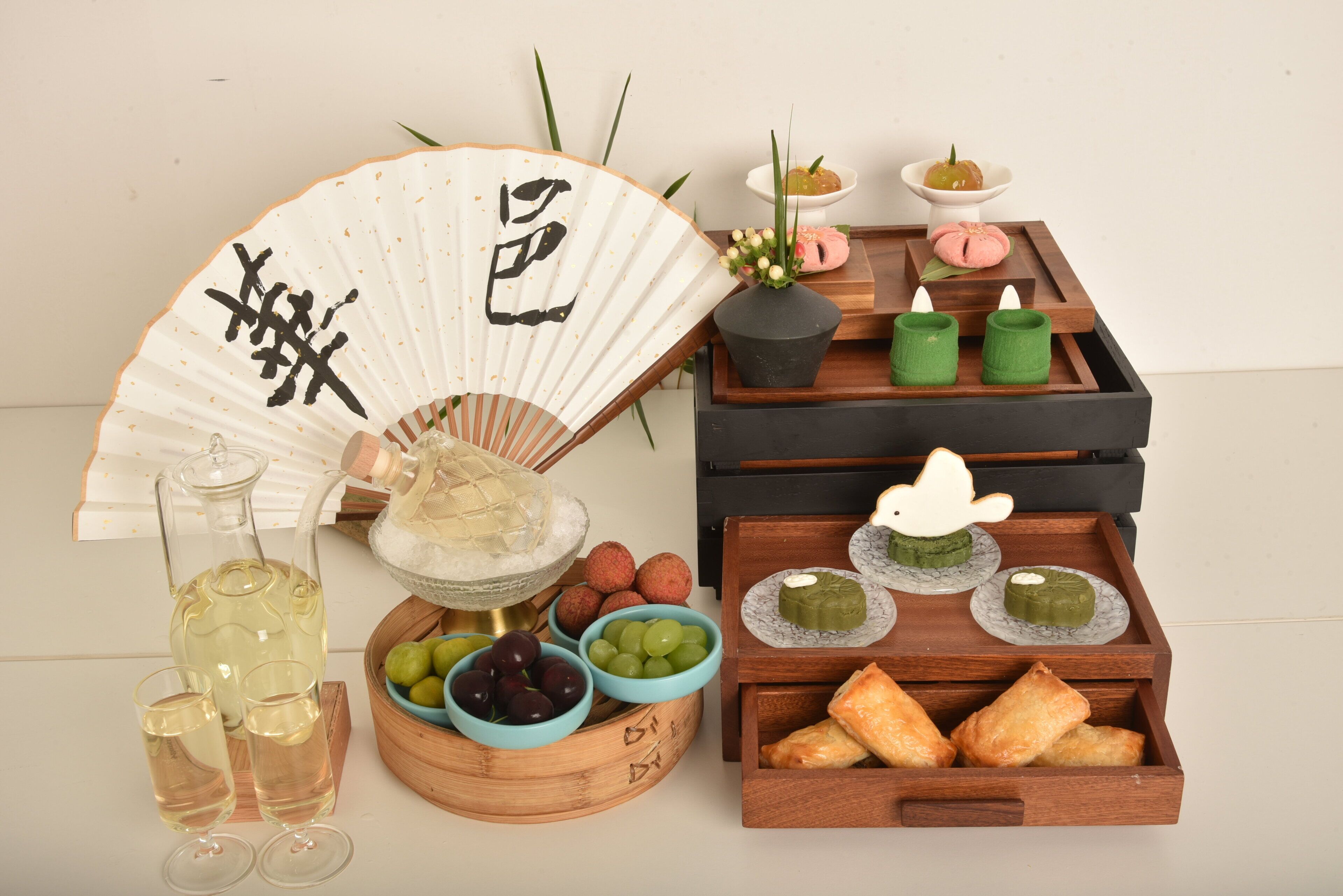 A traditional Japanese tea setting with a fan, tea set, and various sweets.